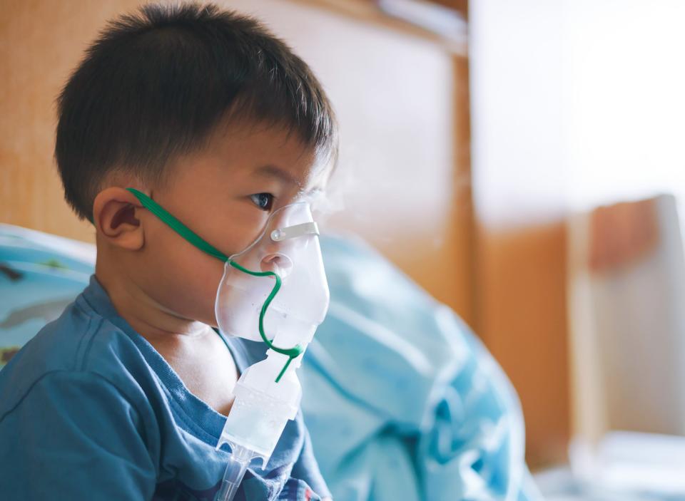 A young boy in hospital uses an inhaler containing medicine to help symptoms of Respiratory Syncytial Virus