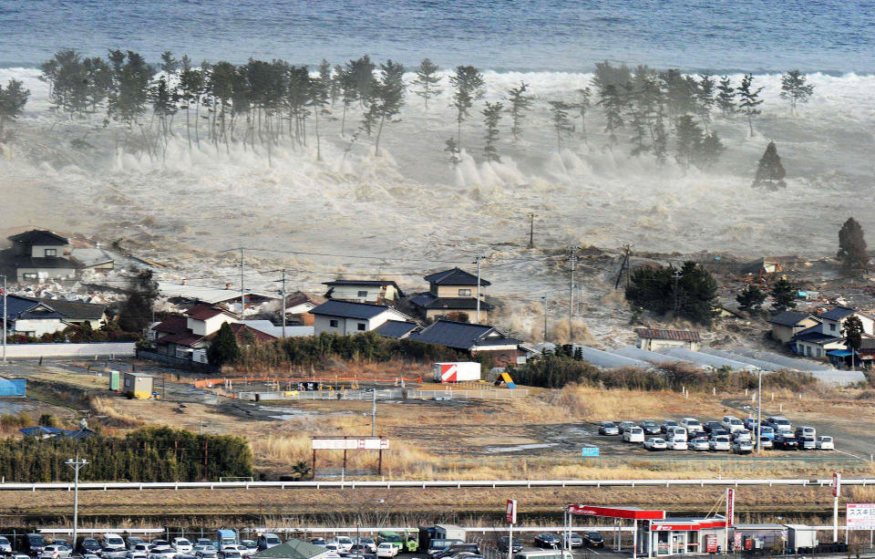 FILE - Waves from a tsunami hit residences after a powerful earthquake in Natori, Miyagi prefecture, Japan, on March 11, 2011. Japan on Monday, March 11, 2024, marked 13 years since a massive earthquake and tsunami hit the country’s northern coasts. (Kyodo News via AP, File)