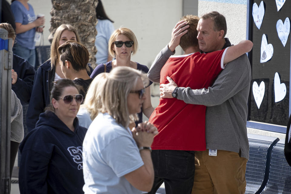 Saugus high principal Vince Ferry, right, gives hugs and welcomes students back on campus Tuesday, Nov. 19, 2019. Students were allowed back to collect their belongings left behind after the tragic shooting last Thursday. Classes will resume at the high school on Dec. 2. (David Crane/The Orange County Register via AP)