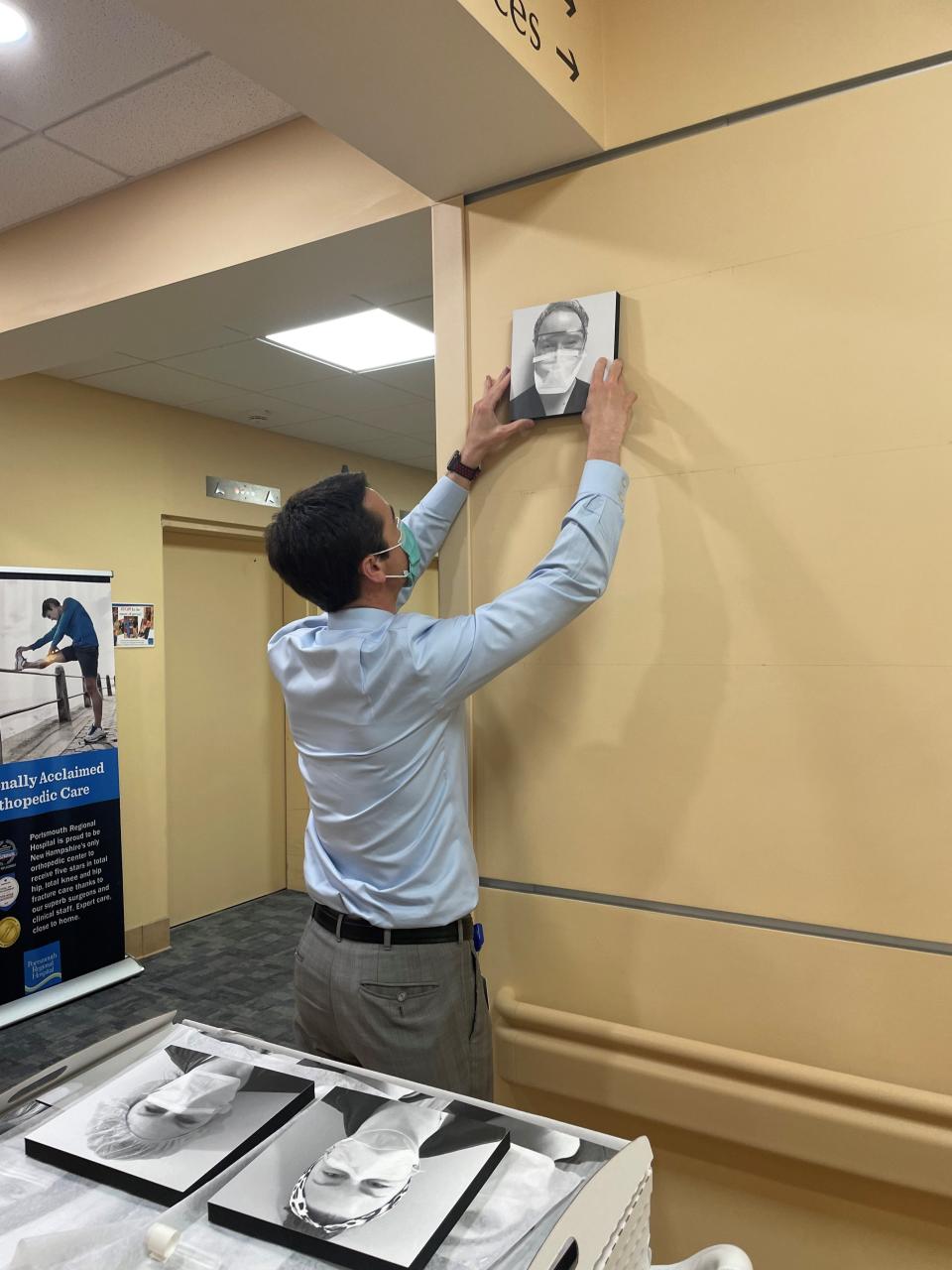 Dean Carucci, CEO of Portsmouth Regional Hospital, hangs the first of more than 500 photos on the walls of the main hallway. Carucci and Megan Gray, Associate Chief Nursing Officer, hung the photos one evening after many employees had gone home for the day.