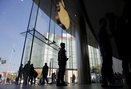 A staff member stands beneath Apple's logo at an apple store in Beijing, November 2, 2015. REUTERS/Kim Kyung-Hoon