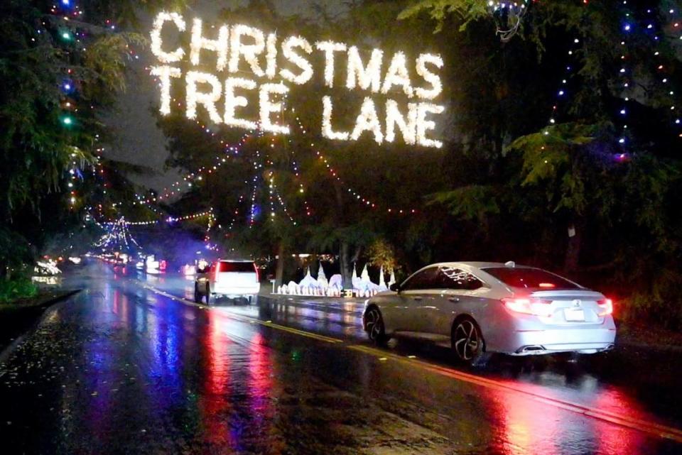Cars make their way along the wet street for the opening night of the 100th year for Christmas Tree Lane in Fresno in 2022.