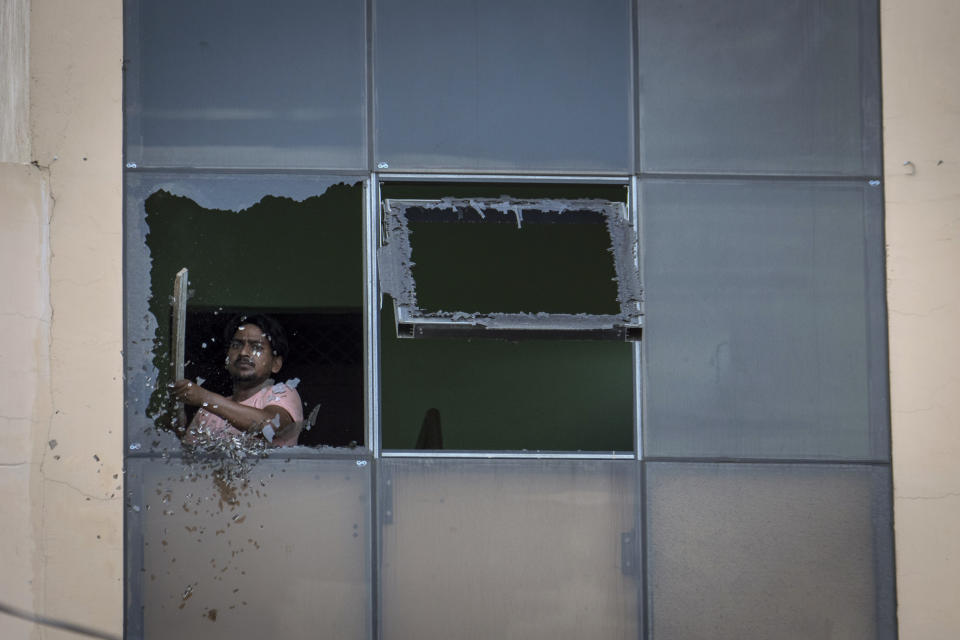 A worker removes broken glass from a window of a restaurant which was partially vandalized during communal clashes in Sohna near Nuh in Haryana state, India, Tuesday, Aug., 1, 2023. Deadly clashes between Hindus and Muslims began in the area Monday afternoon during a religious procession by a Hindu nationalist group forcing Indian authorities to impose a curfew and suspend Internet services. (AP Photo/Altaf Qadri)