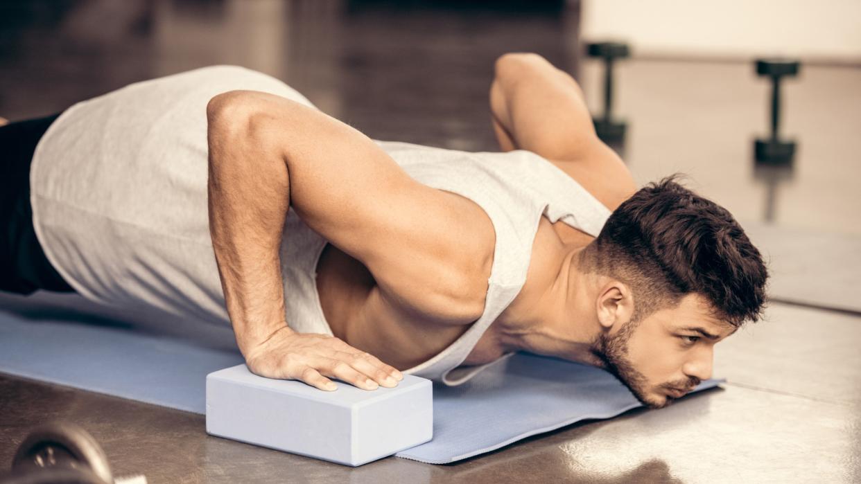  Man in a push-up position with hands on yoga blocks during workout. 
