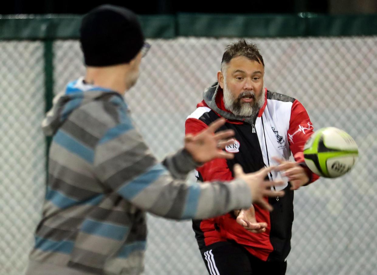 Kitsap Rugby Club Renegades coach Oliver (Ollie) Otterbeck, right, makes a pass while going over drill instructions during practice on the softball field at Naval Base Kitsap-Bangor on March 7.