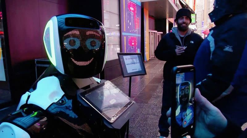 Passers-by in Times Square interact with a Promobot robot that informs the public about the symptoms of coronavirus and how to prevent it from spreading, in this still frame obtained from video, in New York City