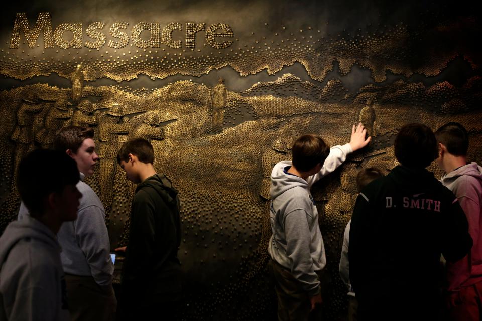 Eighth grade students from St. Joseph School in Cold Springs, Ky., touch a relief image created with bullet casings at the Holocaust & Humanity Center inside the Cincinnati Museum Center in Cincinnati on Wednesday, Feb. 5, 2020.