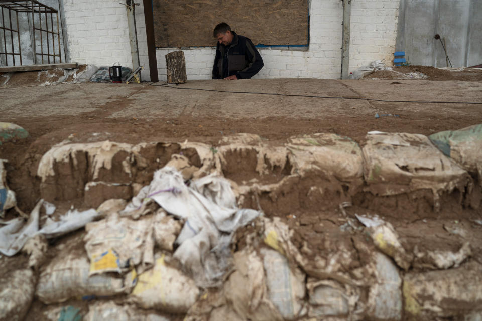 An employee enters a shelter in an area at the Veres farm in Novomykolaivka, eastern Ukraine, Saturday, Sept. 10, 2022. All work has halted on this large eastern Ukrainian farm, whose fields and compound have been hit so many times by mortars, rockets, missiles and cluster bombs that its workers are unable to sow the crater-scarred land or harvest any crops. (AP Photo/Leo Correa)