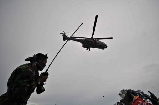 An Indonesian soldier guides a military helicopter to the rescue base on Mount Salak close to the crash site of the Russian Sukhoi Superjet 100. A search team found the black box Tuesday of a Russian jet six days after it slammed into a dormant volcano in Indonesia during a promotional flight, killing all 45 on board