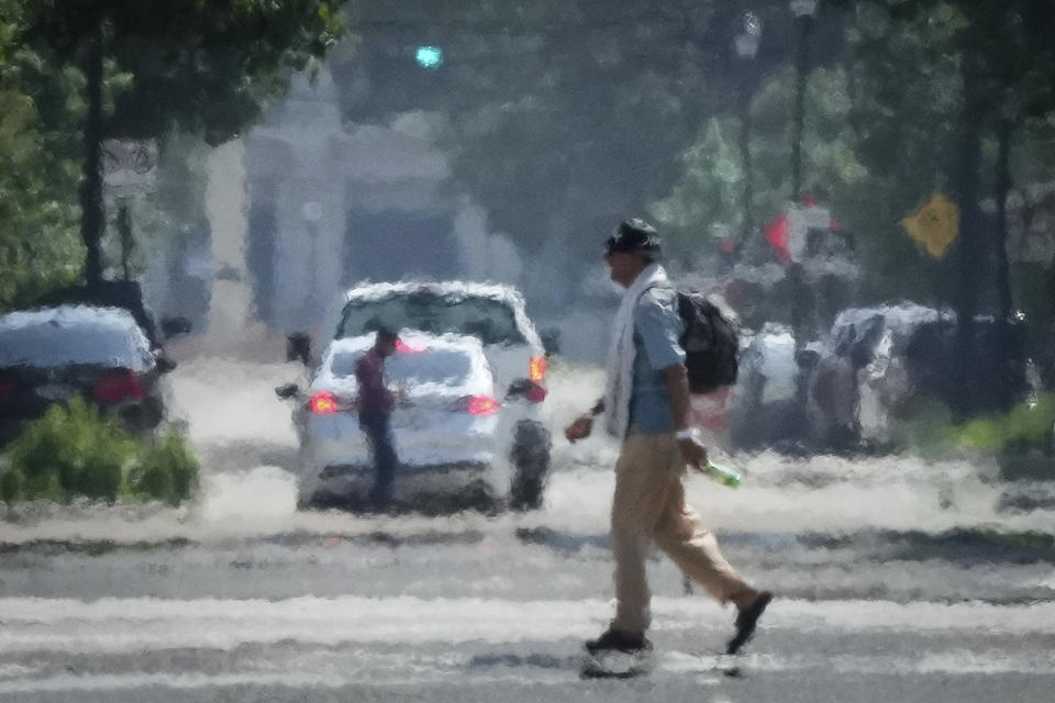 A person crosses Caroline Street in the afternoon heat Saturday, May 25, 2024, near Discovery Green in Downtown Houston. (Jon Shapley/Houston Chronicle via AP)