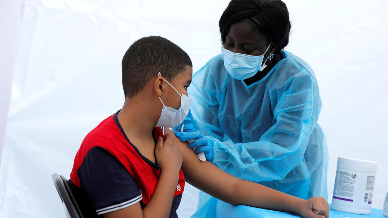 12-year-old Justing Concepcion receives a dose of the Pfizer-BioNTech vaccine for the coronavirus disease (COVID-19) from registered nurse Angela Nyarko, during a vaccination event for local adolescents and adults outside the Bronx Writing Academy school in the Bronx borough of New York City, New York, U.S., June 4, 2021. (Mike Segar/Reuters)