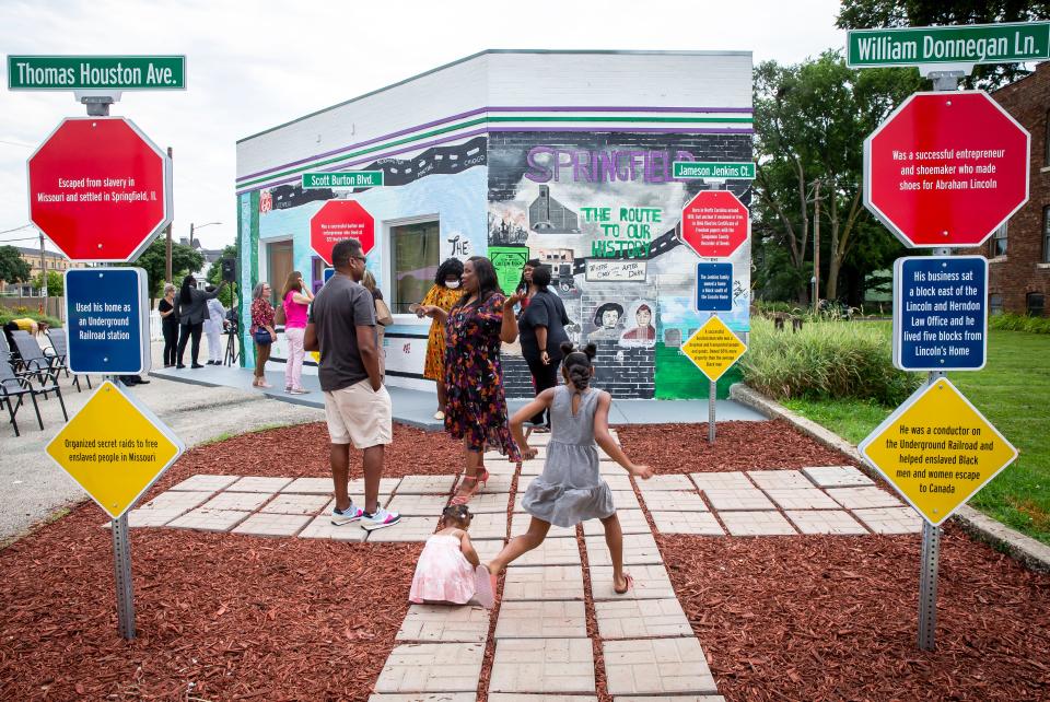 Visitors walk through the tribute to four important Black entrepreneurs in Springfield, two of whom were killed in the 1908 Springfield Race Riot, after a ribbon cutting ceremony for the Route History museum and visitors center in Springfield, Ill., Friday, July 9, 2021. Route History highlights stories around the Black experience on historic Route 66 and is located on East Cook Street. [Justin L. Fowler/The State Journal-Register]