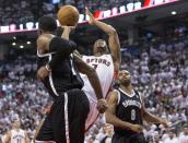 Toronto Raptors' Kyle Lowry is fouled as he drives between Brooklyn Nets' Joe Johnson, left, and Alan Anderson during the first half of Game 1 of an opening-round NBA basketball playoff series, in Toronto on Saturday, April 19, 2014. (AP Photo/The Canadian Press, Chris Young)