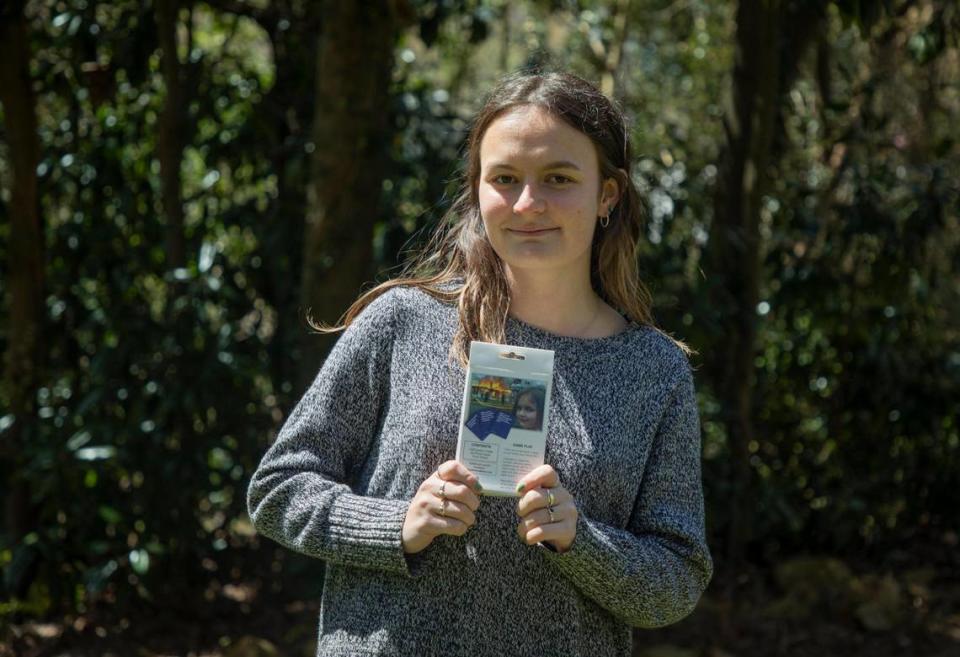 Zoe Roth holds a copy of the game “Know Your Meme” on which a photo of her appears, known as the popular “Disaster Girl” meme, on Friday, Apr. 2, 2021, in Chapel Hill, N.C.