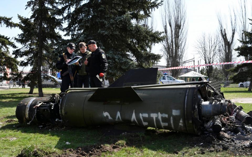 Ukrainian servicemen stand next to a fragment of a Tochka-U missile with writing in Russian reading "For children", after Russian shelling at the railway station in Kramatorsk, Ukraine, Friday, April 8, 2022. - Andriy Andriyenko/AP