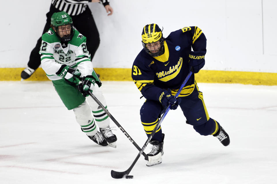 Michigan forward Frank Nazar III (91) gets past North Dakota forward Owen McLaughlin (22) during the first period of an NCAA college hockey tournament regional game in Maryland Heights, Mo., Friday, March 29, 2024. (AP Photo/Colin E. Braley))