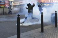 A protestor kicks back a tear gas grenade fired by French police during a demonstration in Marseille, southern France, Saturday, Jan. 12, 2019. Paris brought in armored vehicles and the central French city of Bourges shuttered shops to brace for new yellow vest protests. The movement is seeking new arenas and new momentum for its weekly demonstrations. Authorities deployed 80,000 security forces nationwide for a ninth straight weekend of anti-government protests. (AP Photo/Claude Paris)