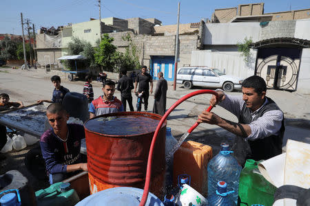 People collect water in containers on a street in eastern Mosul, Iraq, April 19, 2017. REUTERS/Marko Djurica