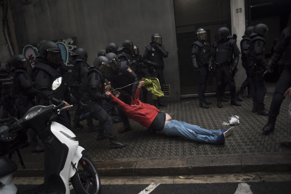 Riot police drag a member of the public away from a school being used as a polling station.