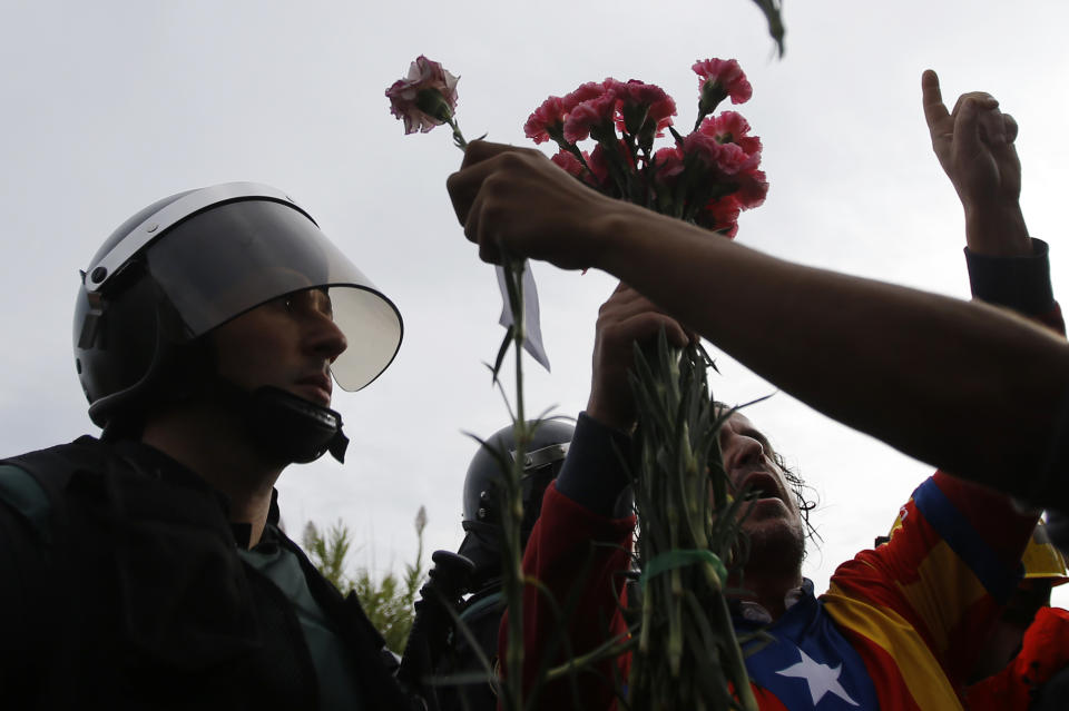 <p>People try to offer flowers to a civil guard at the entrance of a sports center, assigned to be a referendum polling station by the Catalan government in Sant Julia de Ramis, near Girona, Spain, Oct. 1, 2017. Scuffles have erupted as voters protested while dozens of anti-rioting police broke into a polling station where the regional leader was expected to show up for voting on Sunday. (Photo: Francisco Seco/AP) </p>