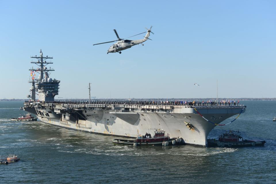 A large ship with a helicopter hovering above it.