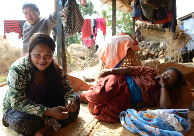 Nepalese migrant worker Sunita Magar (L), who was trafficked to Syria, sits with her mother (R) and father (back) at their home in Dhadhing district, some 100 km west of Kathmandu