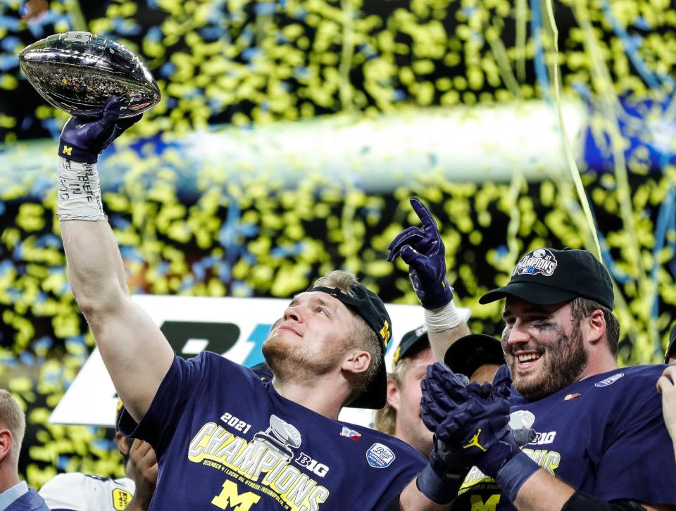 Michigan defensive end Aidan  Hutchinson lifts the championship trophy after the Wolverines defeated Iowa 42-3 in the Big Ten Championship Game on Dec. 4 in Indianapolis.