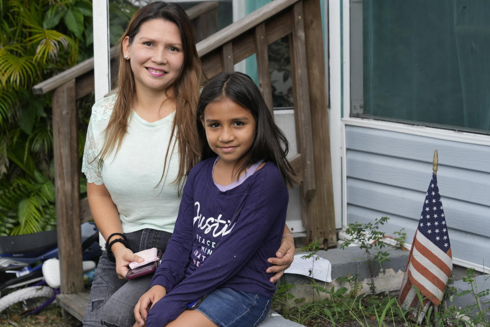 Deisy Mori and her daughter Abril, sit near their home, Wednesday, Sept. 27, 2023, in Davie, Fla. Mori and her husband left Venezuela five years ago, after hooded paramilitaries entered their home and threatened them with death for having participated in street demonstrations demanding freedom of expression and free elections. She was imprisoned and her husband hospitalized for his injuries. The family entered the U.S., over a year ago. They were granted temporary protected status following a recent announcement by the Biden administration. (AP Photo/Marta Lavandier)