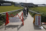 Quarantine officials wearing protective gear stand as a precaution against African swine fever at a pig farm in Paju, South Korea, Tuesday, Sept. 17, 2019. South Korea is culling thousands of pigs after confirming African swine fever at a farm near its border with North Korea, which had an outbreak in May. The notice reads: "Under quarantine." (AP Photo/Ahn Young-joon)