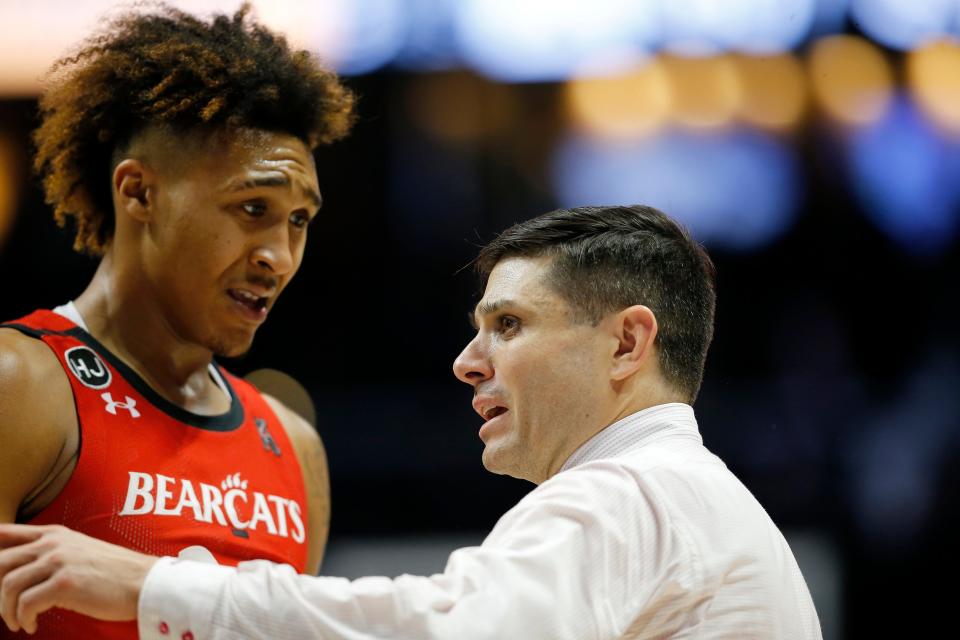 Cincinnati Bearcats head coach Wes Miller talks with guard Jeremiah Davenport (24) in a timeout in the second half of the 89th Annual Crosstown Shootout basketball game between the Xavier Musketeers and the Cincinnati Bearcats at the Cintas Center in Cincinnati on Saturday, Dec. 11, 2021. Xavier head coach Travis Steele improves his record in the rivalry to 3-1 as the Musketeers won 83-63. 