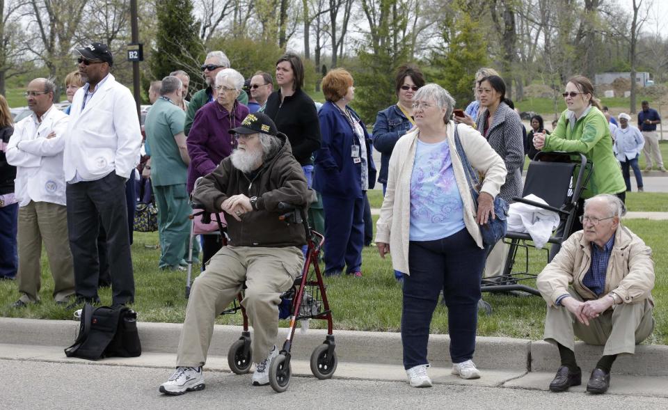 People wait outside a Veterans Affairs hospital after they were evacuated, Monday, May 5, 2014, in Dayton, Ohio. A city official says a suspect is in police custody after a shooting at the Veterans Affairs hospital in Ohio that left one person with a minor injury. (AP Photo/Al Behrman)