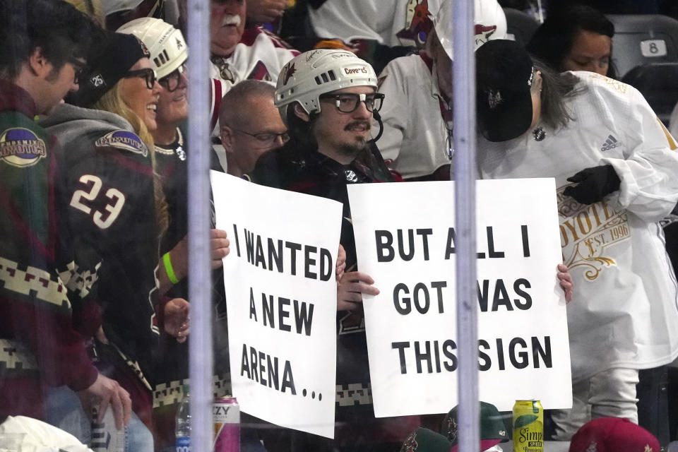 Arizona Coyotes fans hold up signs during the second period of the team's NHL hockey game against the Edmonton Oilers on Wednesday, April 17, 2024, in Tempe, Ariz. The Coyotes are moving to Salt Lake City in a deal that could be signed less than 24 hours after the game. Hockey could return, perhaps within five years, but the stark reality is this is the end for the foreseeable future. (AP Photo/Ross D. Franklin)