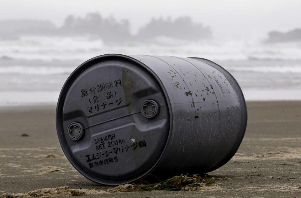 A cannister with Japanese writing is washed up on the beach. Marine debris experts believe that ocean currents are carrying some of the timber, refrigerators, fishing boats and other objects across the Pacific.