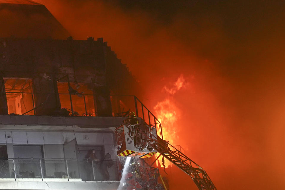 Firefighters rescue two people who were trapped on a balcony in a burning housing block in Valencia, Spain, Thursday, Feb. 22, 2024. The cause of the fire is unknown and if there are any victims. (AP Photo/Alberto Saiz)