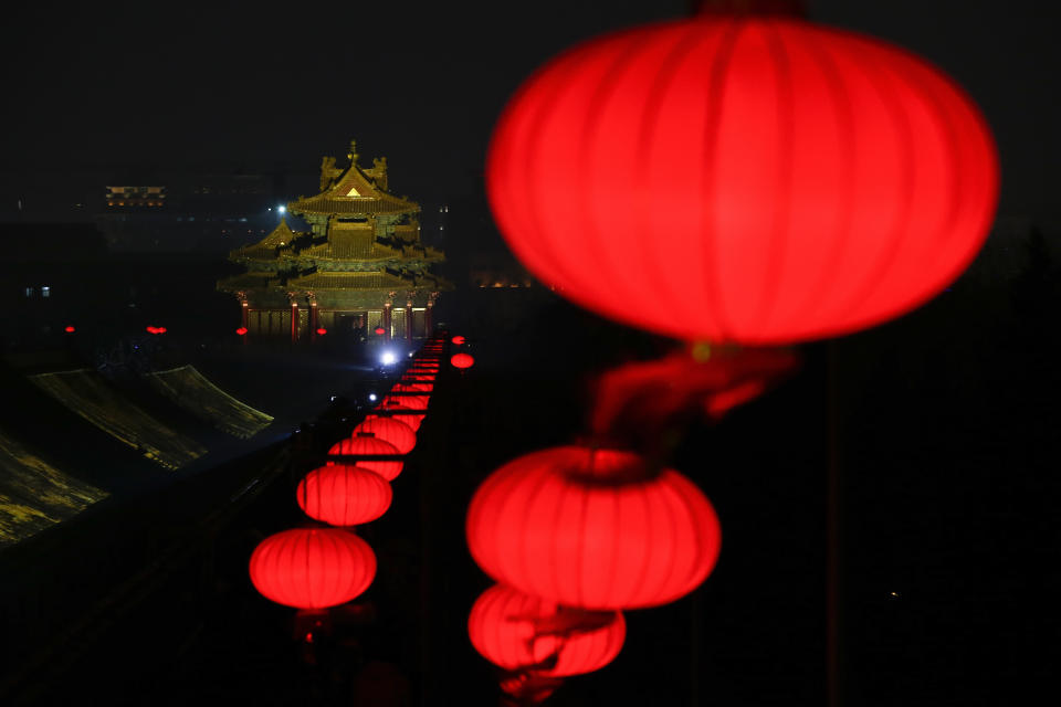 In this Tuesday, Feb. 19, 2019, photo, lanterns is decorated near a Turret of the Forbidden City projected with lights for the Lantern Festival in Beijing. China lit up the Forbidden City on Tuesday night, marking the end of 15 days of lunar new year celebrations. It was not a Lantern Festival the last emperor, who abdicated in 1912, would have recognized. There were lanterns, but those lucky enough to snag tickets saw a laser light show and historic buildings bathed in colorful lights. Others watched from outside the vast walled compound in Beijing, from where Ming and Qing dynasty emperors ruled for five centuries.(AP Photo/Andy Wong)