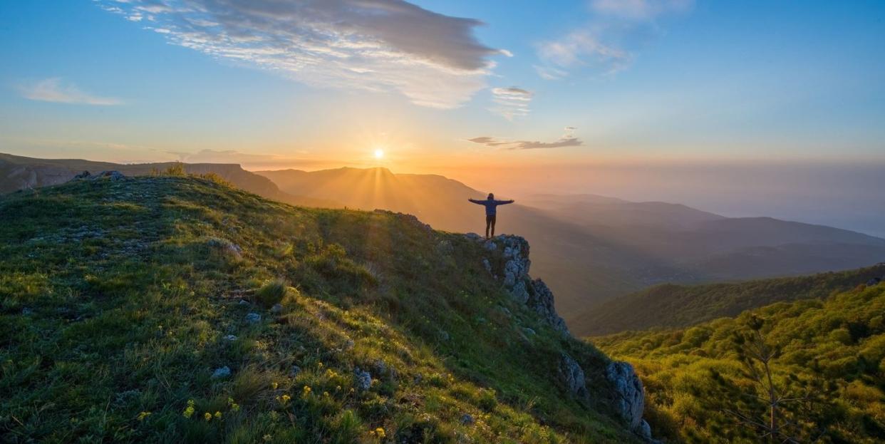 inspirational quotes person standing on a mountain with arms up towards sky