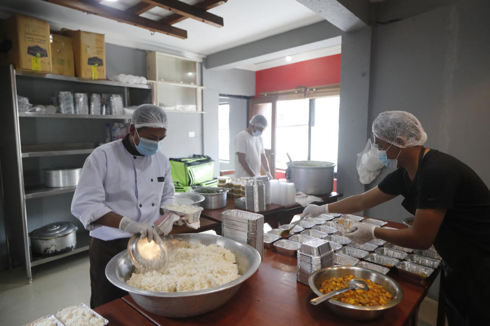 Taxi driver Indra Kumar Newar, right, packs food along with a volunteer to deliver to Teaching Hospital in Kathmandu, Nepal, Friday, Aug. 28, lead 2020. At one of the largest hospitals in Nepal, Newar and his pharmacist friend have teamed up to feed COVID-19 patients, doctors, nurses and health workers. Due to lockdowns, the cafeteria and nearby cafes have closed, leaving more than 200 staffers, patients and their families without food. The two friends have taken their own money and donations and put it to use buying groceries, renting a kitchen and paying helpers to provide the meals. (AP Photo/Niranjan Shrestha)