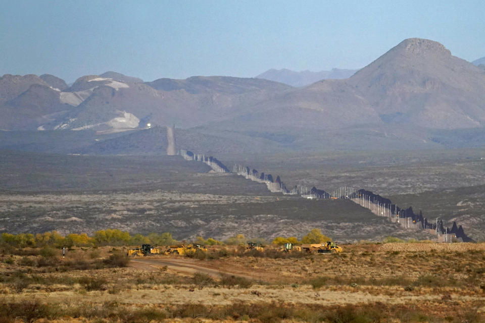 The newly erected border wall, that separates the United states and Mexico, right, leads towards the dynamited mountaintop path, Tuesday, Dec. 8, 2020, as seen from Douglas, Ariz. Construction of the border wall, mostly in government owned wildlife refuges and Indigenous territory, has led to environmental damage and the scarring of unique desert and mountain landscapes that conservationists fear could be irreversible. (AP Photo/Matt York)