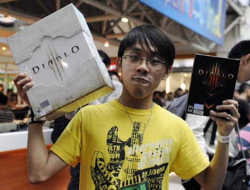 Clerk Seth Chan, 24, poses with his newly released copy of Diablo III and a collector's edition for being the first in line at the videogame's launch event at a computer mall in Singapore on May 15, 2012. Thousands of people queud outside the mall, many of them taking time off from work or school to grab their copies. (AFP Photo/Simin Wang)