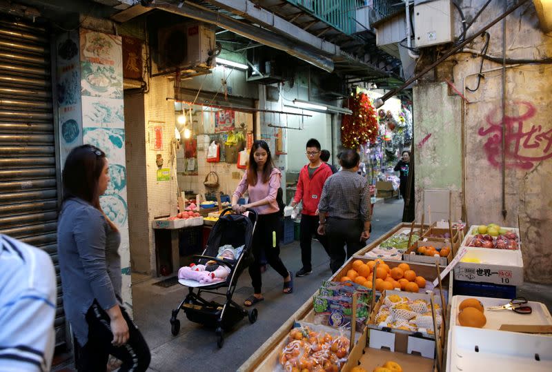 People walk past roadside stalls in an alley in Macau