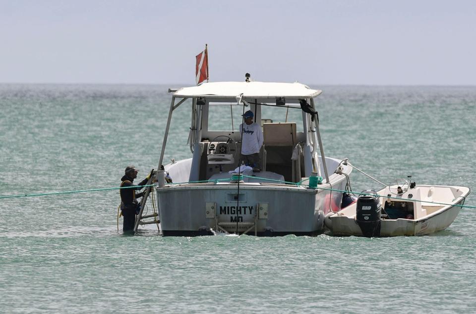 Michael Perna (left) and Milan "Choppy" Kalelkar work a few hundred yards off the shoreline near Ambersand Beach, Aug. 17, 2023, in Indian River County. The Mighty Mo, an ex-Navy utility launch that was used as a dinghy for a battleship, was named after Perna's mentor Demostenes "Mo" Molinar. The boat was decommissioned and used as a tow boat in St. Augustine before Perna purchased it in 2010 and converted it into a research vessel.