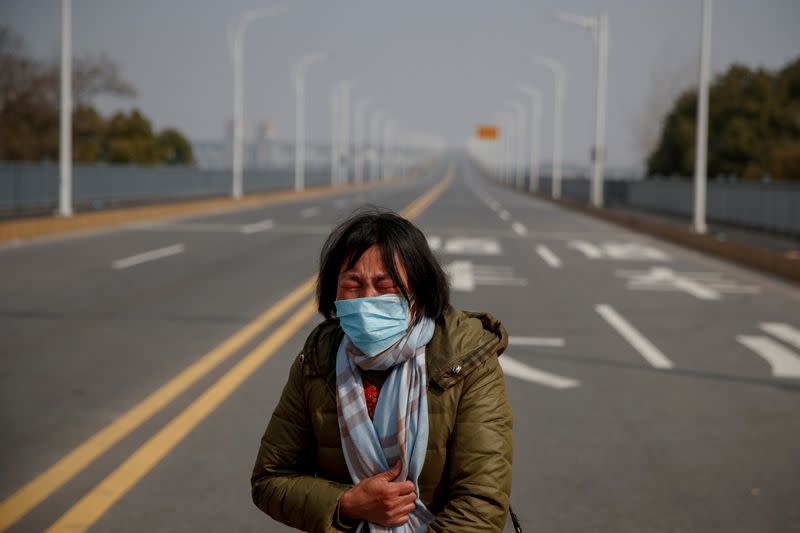 A mother reacts as she pleads with police to allow her daughter to pass a checkpoint for cancer treatment after she arrived from Hubei province at the Jiujiang Yangtze River Bridge in Jiujiang