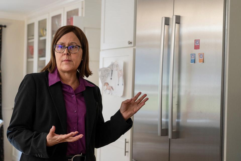 Jennifer Devening, the CEO of Your Health, gestures to the Your Health QR codes she keeps on her refrigerator door.
