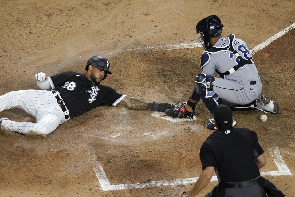 Chicago White Sox's Leury Garcia (28) scores next to Tampa Bay Rays catcher Francisco Mejia on a hit by Danny Mendick and a throwing error by left fielder Randy Arozarena, as home plate umpire James Hoye watches during the fourth inning of a baseball game Tuesday, June 15, 2021, in Chicago. (AP Photo/Charles Rex Arbogast)