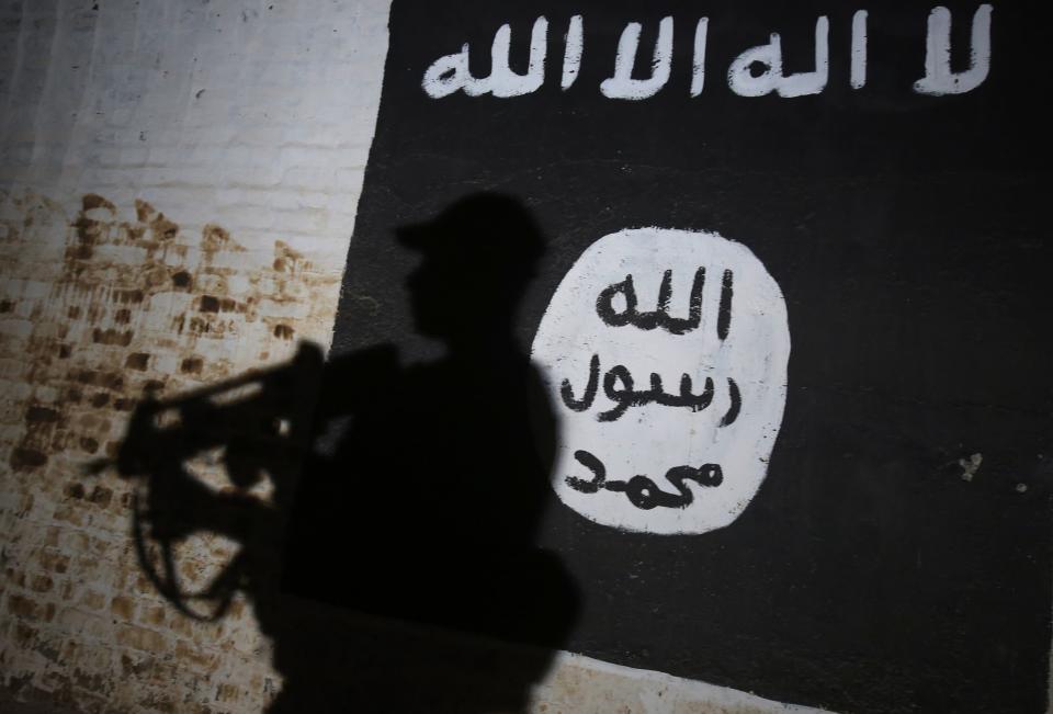 A member of the Iraqi forces walks past a mural bearing the logo of the Islamic State (IS) group in a tunnel that was reportedly used as a training centre by the jihadists, on March 1, 2017, in the village of Albu Sayf, on the southern outskirts of Mosul. (Ahmad Al-Rubaye/AFP via Getty Images)