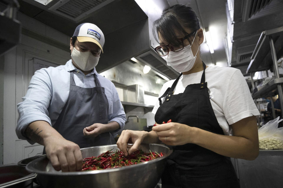 Volunteers of COVID Thailand Aid, Chef Chalee Kader, left, from Thailand, and Chef Saki Hoshino from Japan prepare chili for "pad krapow gai", the spicy minced chicken for the railway-side community at Bo.lan restaurant in Bangkok, Thailand, Wednesday, June 10, 2020. Thailand's Natalie Bin Narkprasert, who runs a business in Paris, was stranded in her homeland by a flight ban, so she decided to use her skills to organize the network of volunteers, including Michelin-starred chefs, to help those in her homeland whose incomes were most affected by the pandemic restrictions. (AP Photo/Sakchai Lalit)
