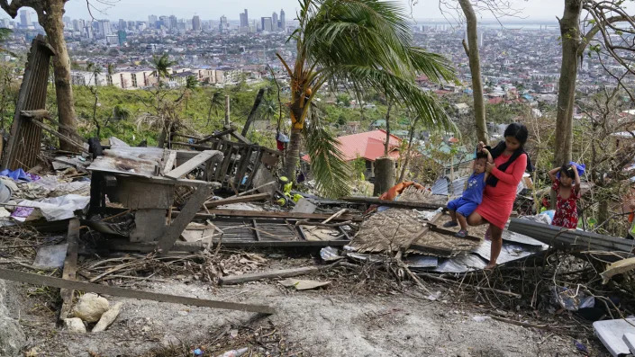 Alona Nacua carries her son over debris from their house destroyed by Typhoon Rai in Cebu City, central Philippines, on Christmas Day.