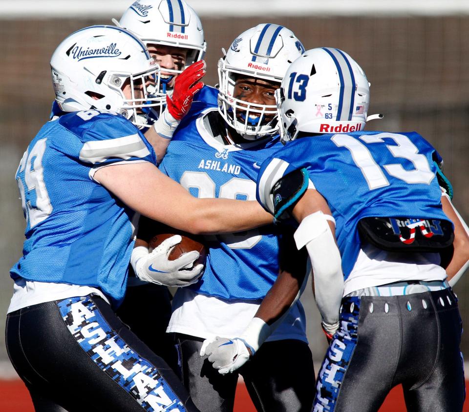 Ashland’s#23 Kevin Ozulumba (center) gets congratulations from teammates after running in for a touchdown during the 100th Thanksgiving Day football meeting with Hopkinton at Ashland High.