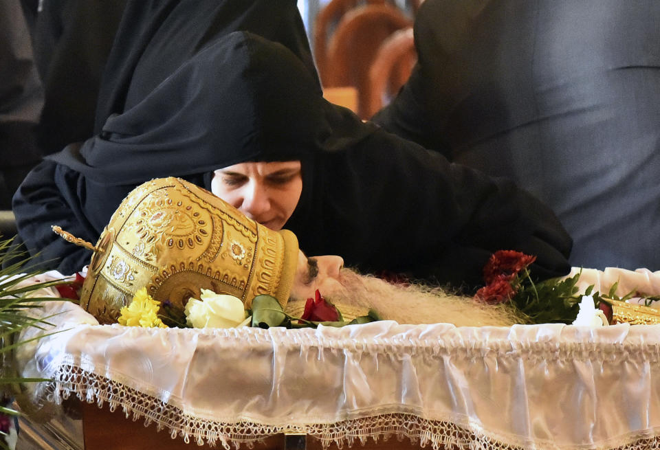 A nun kisses the Bishop Amfilohije's body during the liturgy and funeral in the main temple in the capital Podgorica, Montenegro, Sunday, Nov. 1, 2020. Bishop Amfilohije died on Friday after contracting the coronavirus weeks ago. A mass funeral on Sunday was held for the popular head of the Serbian Orthodox Church in Montenegro in violation of restrictions that are in place against the new coronavirus. (AP Photo/Risto Bozovic)