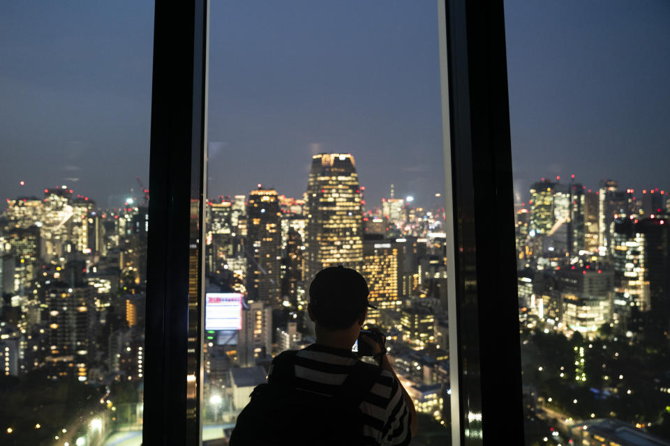 A visitor takes pictures of Tokyo's skyline from Tokyo Tower's observation deck Friday, Sept. 27, 2019, in Tokyo. Standing at 1092 feet, the tower is the second tallest structure in Japan. (AP Photo/Jae C. Hong)